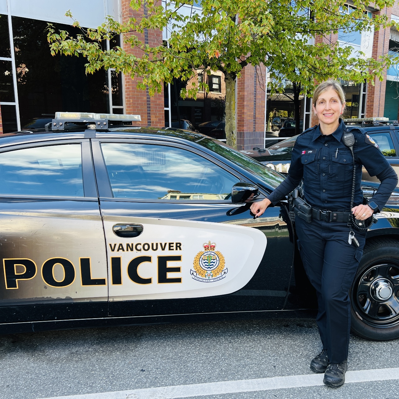Cst. Holly Christie posing beside a VPD police car at 2120 Cambie Headquarters