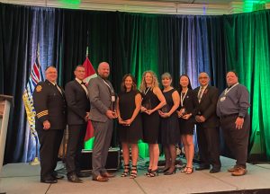 Award winners and presenters on stage smiling for camera at APCO Canada awards ceremony.